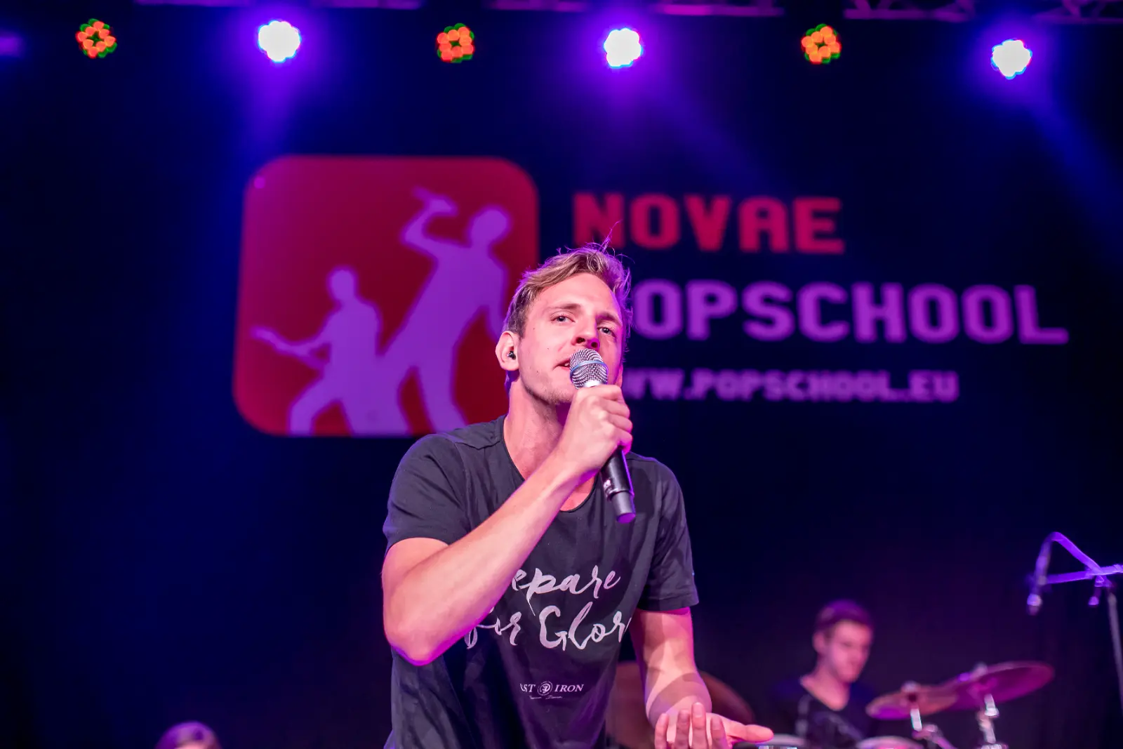 Zanger vol in het licht op het eindfestival, drummer op de achtergrond