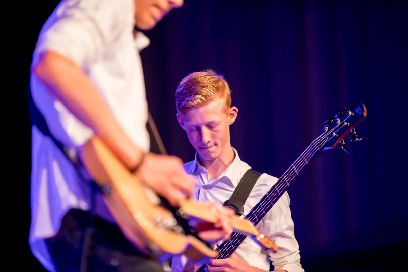 Bassist kijkt naar zijn snaren, gitarist onscherp op de voorgrond